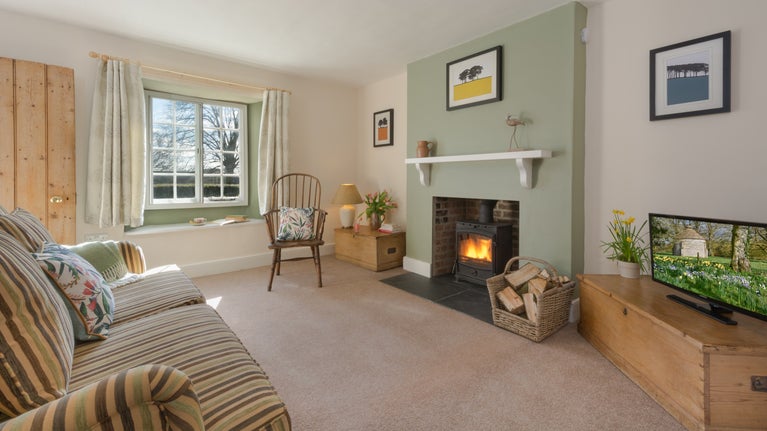 The sitting room at 3 Lytes Cottage, with sofa, television and woodburner, Somerset